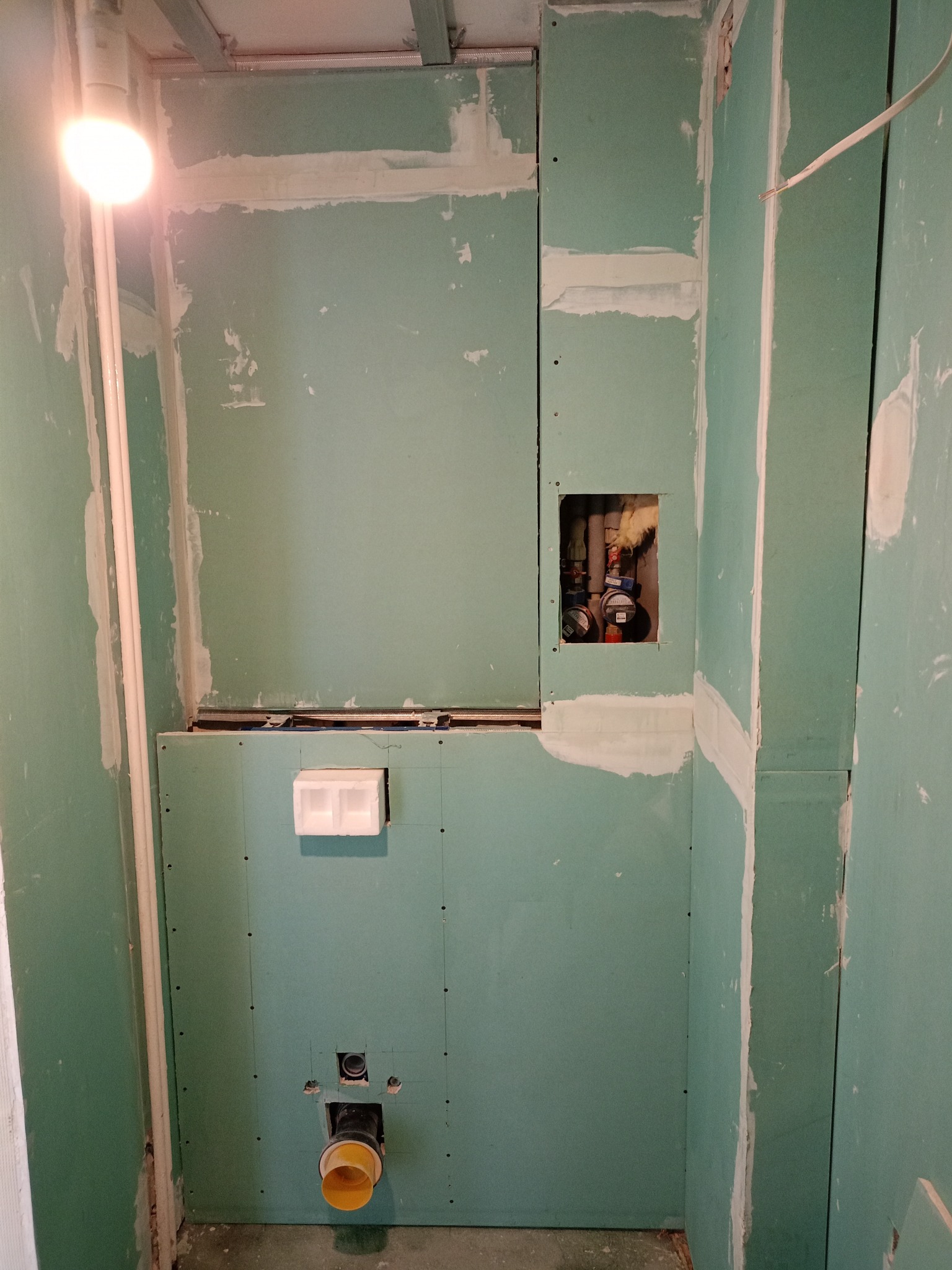 Łazienka w trakcie zabudowy płytami gipsowo-kartonowymi, widoczne instalacje wodne i kanalizacyjne, przygotowanie do dalszych prac wykończeniowych.