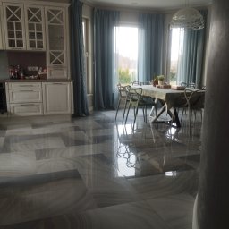 SPB CRYSTAL OLENA KRYCHUN - Błyszcząca, szara podłoga z płytek w przestronnej jadalni we Wrocławiu. Widoczne krzesła, stół nakryty do posiłku i okna z niebieskimi zasłonami.