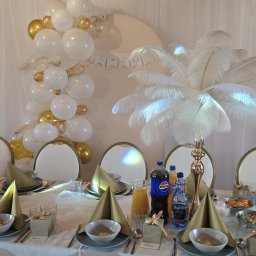 ADbiuro Dorota Adamowska - Uroczysty stół z dekoracjami: biało-złote balony, pióra, elegancka zastawa, prezenciki z imionami gości. Dekoracja na wesele lub inną imprezę okolicznościową.