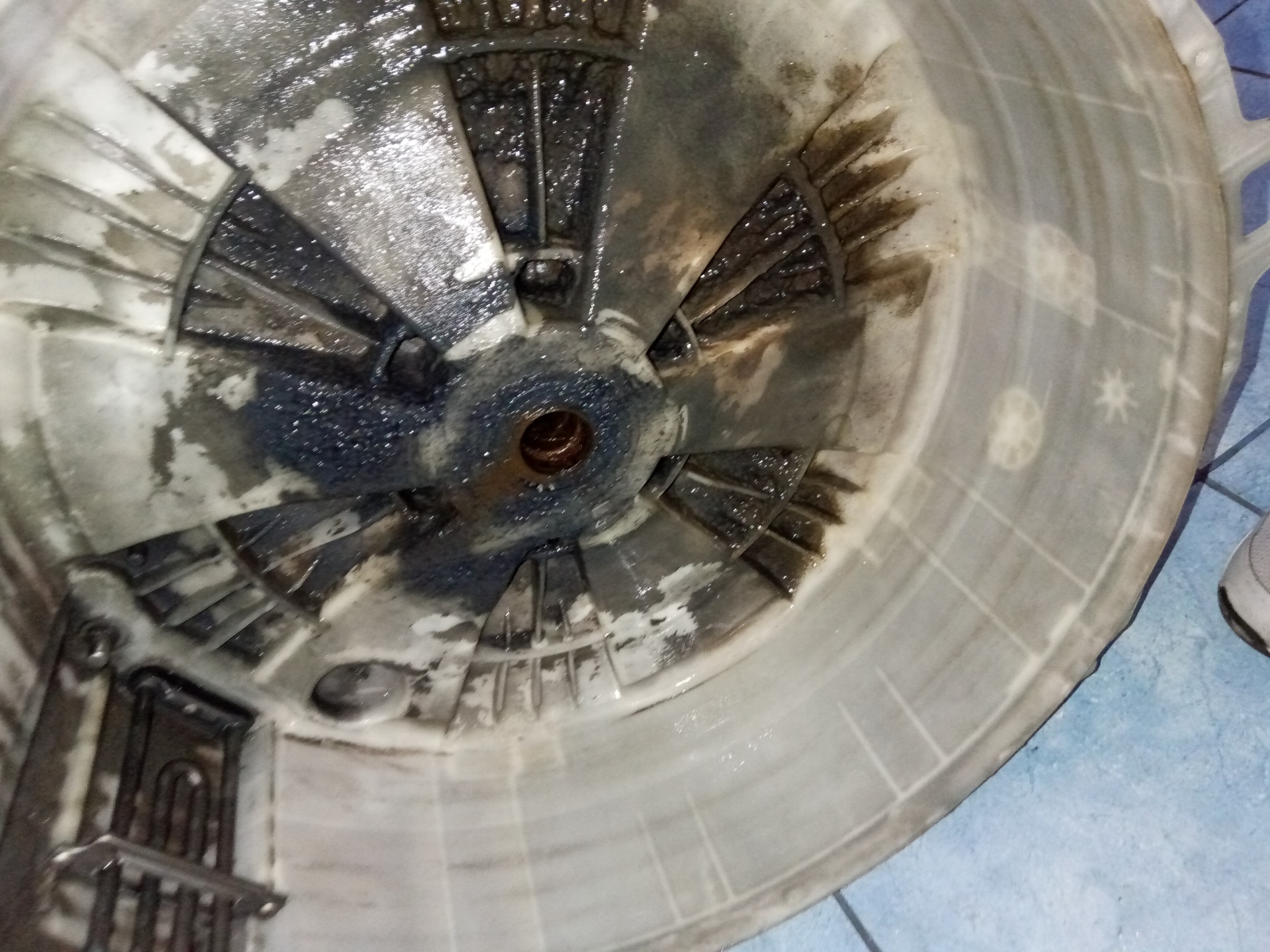 Zdemontowany, zabrudzony bęben pralki automatycznej z widocznymi śladami rdzy i osadów, ukazujący stopień zużycia i potrzebę konserwacji lub naprawy.