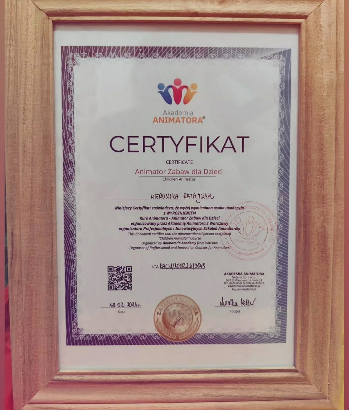 Certyfikat ukończenia kursu animatora zabaw dla dzieci Akademii Animatora w drewnianej ramce, z pieczęcią i podpisem, potwierdzający kwalifikacje Weroniki Ratajczyk.