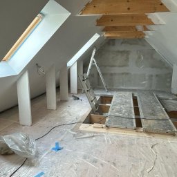 Remontownia25 - Adaptacja poddasza: widok na ocieplone skosy z oknami dachowymi, rusztowanie i drabina. Prace wykończeniowe w toku, podłoga zabezpieczona folią.