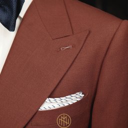 MORGAN & NESS - Brązowy, teksturowany blezer z poszetką w kieszonce, granatowa mucha, ozdobna szpilka w klapie i subtelne logo na kieszeni. Elegancki detal.