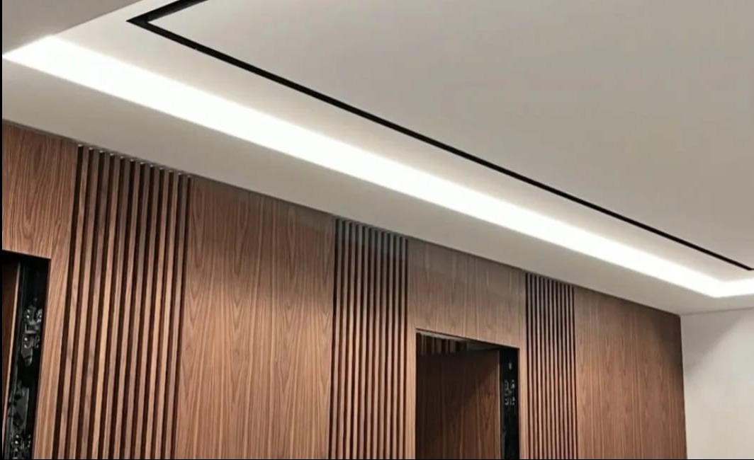 Nowoczesne wykończenie wnętrza z drewnianą okładziną ścienną i liniowym oświetleniem LED w suficie, tworzące elegancki i minimalistyczny design.