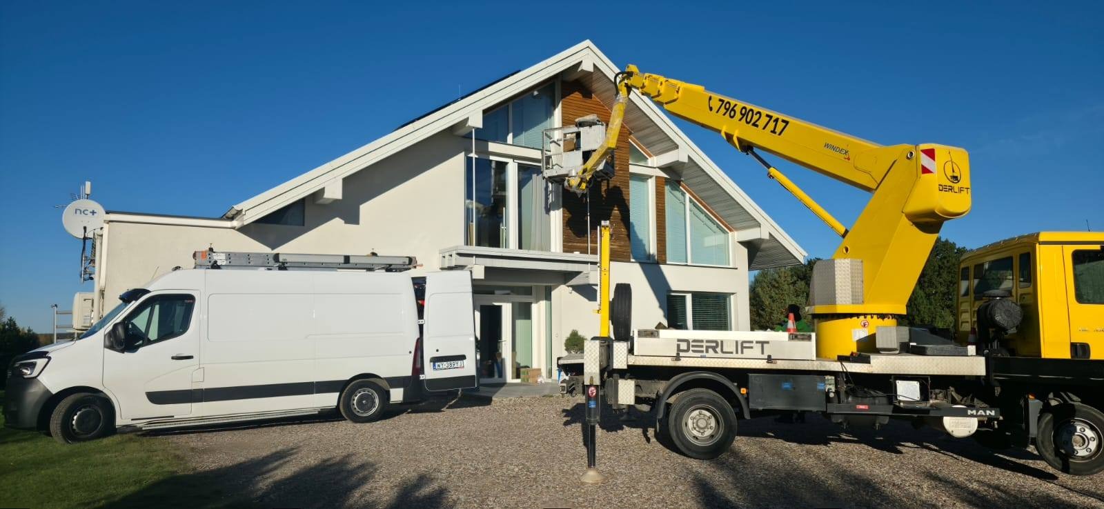 Żółty podnośnik koszowy PERLIFT przy nowoczesnym domu z dużymi oknami. Biały bus z otwartymi drzwiami obok. Antena satelitarna na ścianie. Słoneczny dzień.