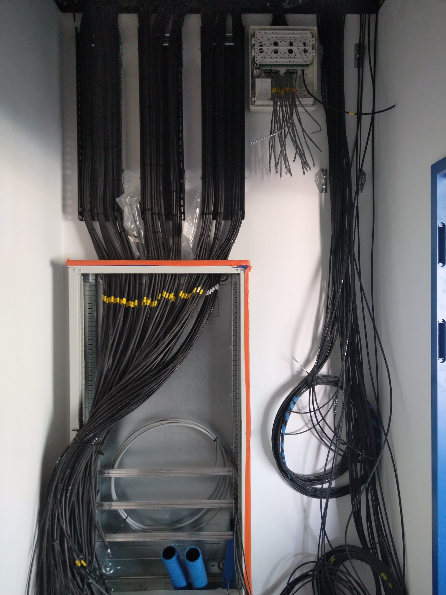 Rozdzielnia elektryczna z licznymi kablami ułożonymi w korytkach i podłączonymi do listwy. Widoczne oznaczenia na kablach i elementy montażowe.