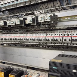 Rostyslav Loichenko - Rozbudowana szafa sterownicza z licznymi bezpiecznikami, stycznikami i okablowaniem. Widoczne elementy marki Siemens i ABB. Precyzyjny montaż w szarej obudowie.