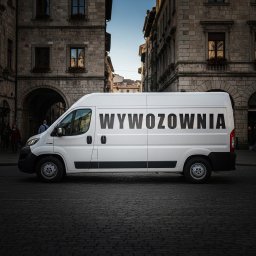 Wywozownia - przeprowadzki, wywozy, transport - Biały furgon z napisem 'WYWOZOWNIA' na tle kamienic w historycznym centrum miasta, zaparkowany na brukowanej ulicy. Perspektywa z boku, oświetlenie dzienne.