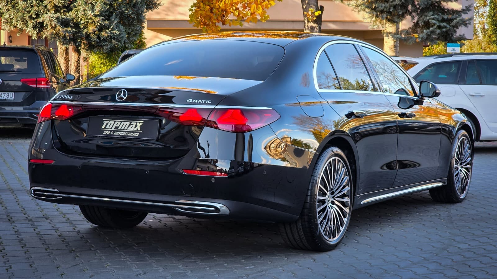 Błyszczący, czarny Mercedes S220d 4MATIC po detailingu, widok z tyłu, z wyraźnym logo 'TOPMAX SPA & AUTODETAILING' na tablicy rejestracyjnej. Jesienne tło.