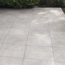 LevelStone Mykhailo Habrus - Jasnoszara, regularna kostka brukowa ułożona na tarasie, z widoczną roślinnością w tle. Minimalistyczny design i precyzyjne wykonanie.