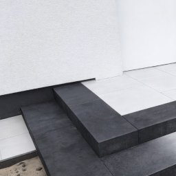 LevelStone Mykhailo Habrus - Nowoczesne schody wejściowe z ciemnej kostki brukowej, kontrastujące z białą elewacją i płytkami. Minimalistyczny design, precyzyjne wykonanie.