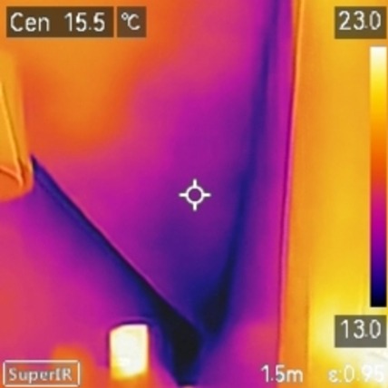 Termowizja ściany ukazuje rozkład temperatur, od chłodnych fioletów po ciepłe pomarańcze i żółcie, z zaznaczonym punktem pomiarowym i skalą temperatur.