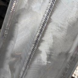 StegWeld - Szlifowana powierzchnia metalu z wyraźnym, precyzyjnym spoiwem spawalniczym. Widoczne ślady obróbki mechanicznej i detale spoiny.