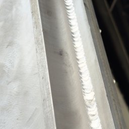 StegWeld - Szlifowany profil metalowy z widocznym spoiną, ukazujący precyzję wykonania i gładką powierzchnię. Detal obróbki metalu z bliska.