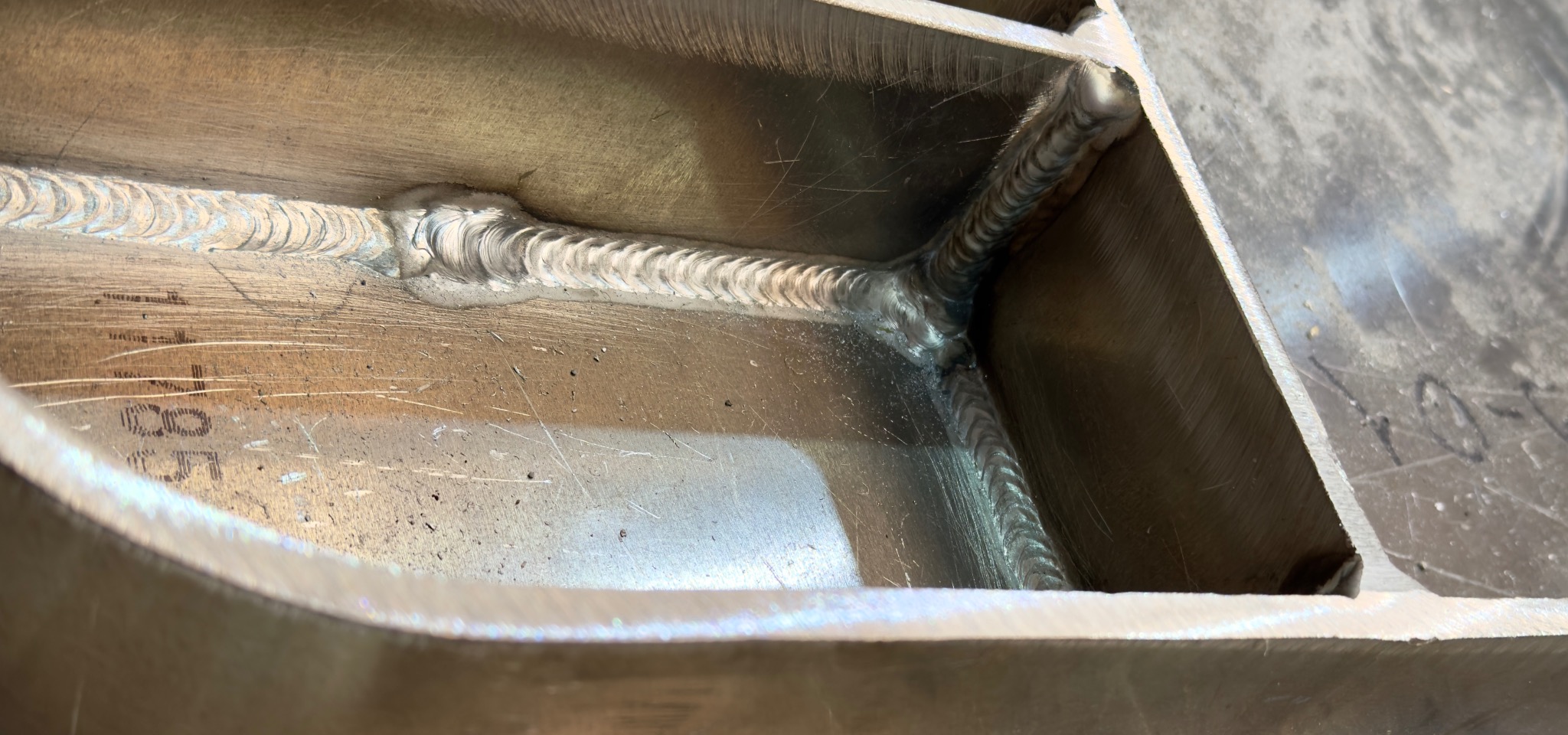 Szczegółowe zbliżenie na precyzyjne spawy łączące metalowe elementy konstrukcji, ukazujące estetyczne i trwałe połączenie. Widoczne ślady obróbki.