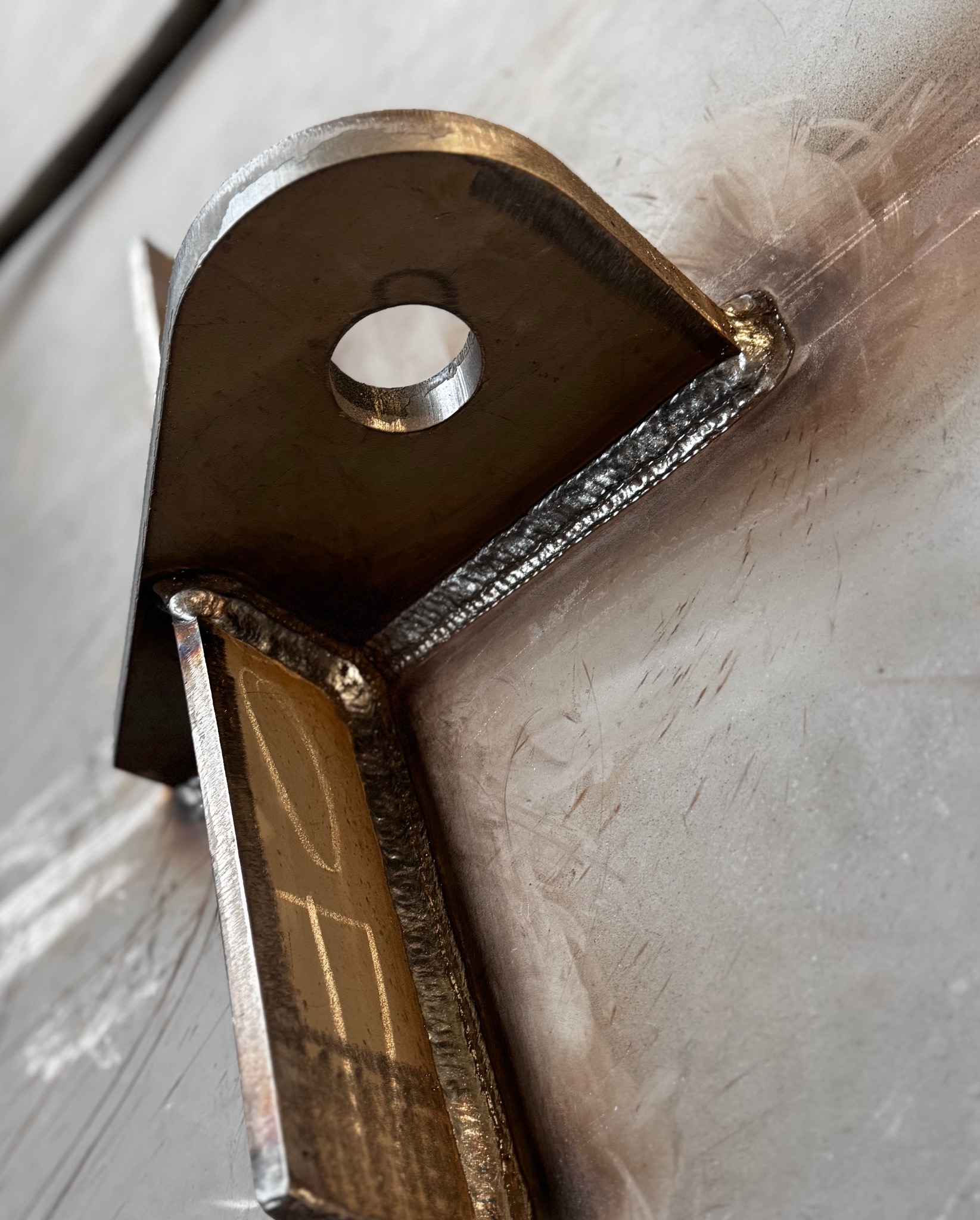 Precyzyjne spawy łączące metalowe elementy konstrukcyjne pod kątem, widoczne detale spoin i obróbki, surowy metaliczny wygląd.