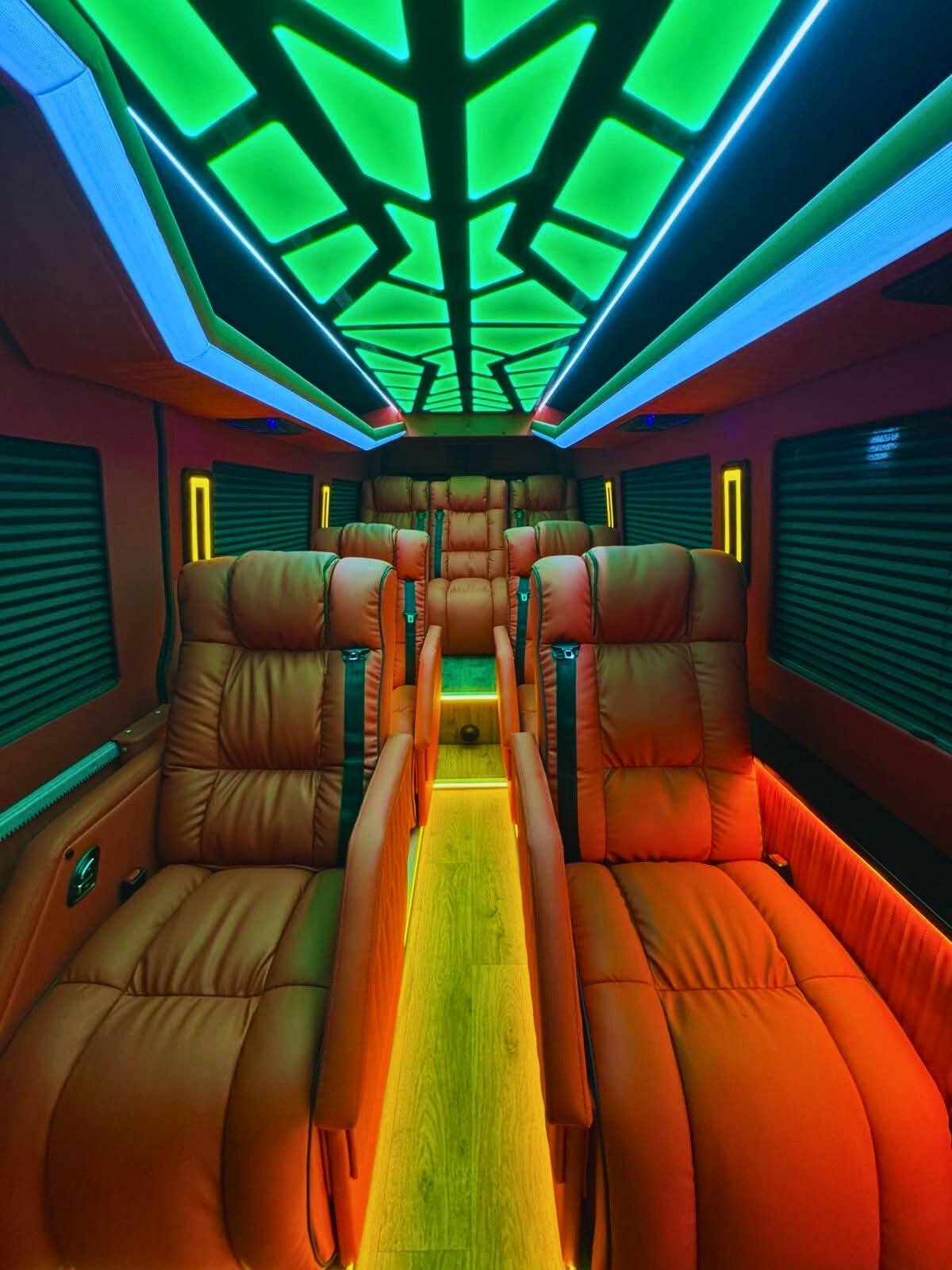Luksusowe wnętrze busa z skórzanymi fotelami, podświetlanym sufitem i podłogą. Komfortowe warunki podróży, idealne na przewóz osób lub transport VIP.