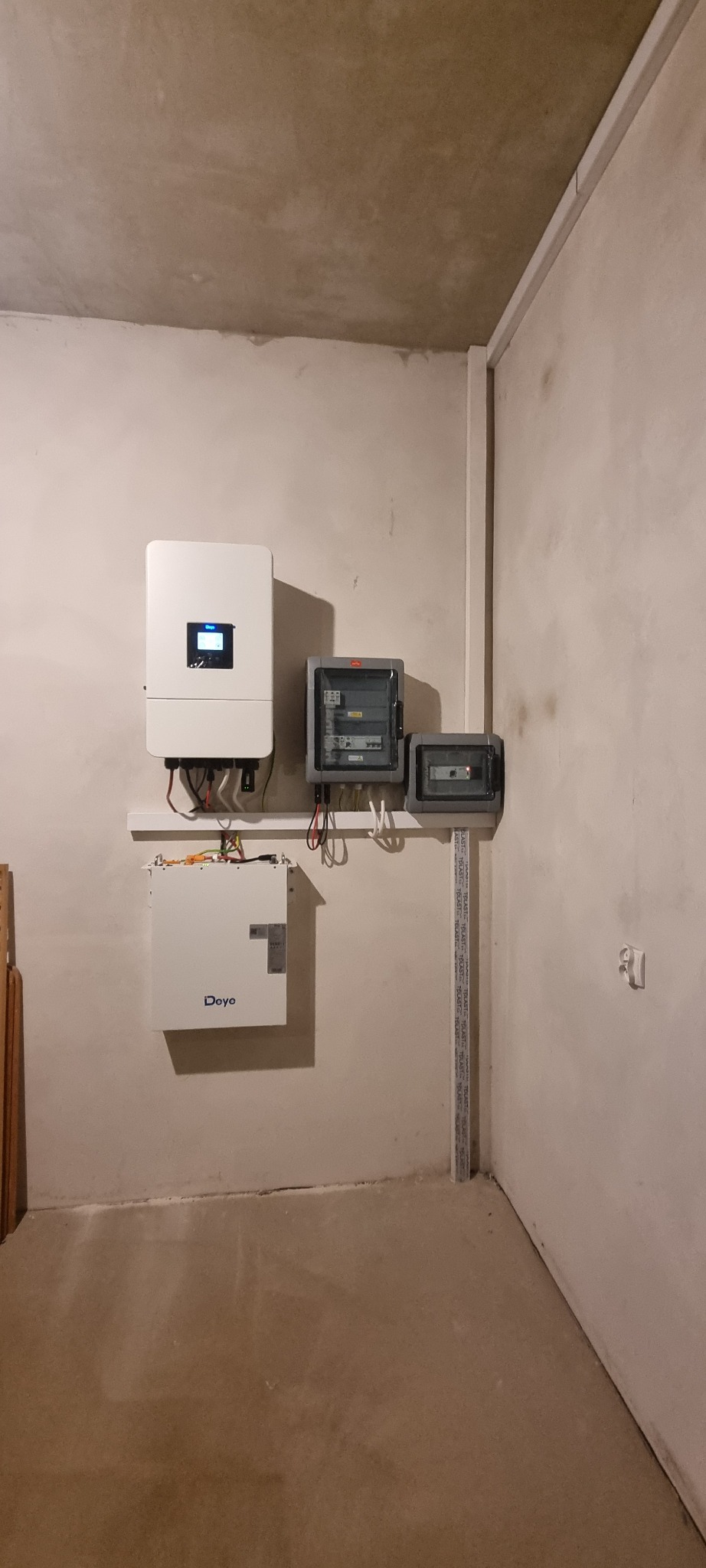Kompletna instalacja fotowoltaiczna wewnątrz budynku: inwerter, magazyn energii Deye i rozdzielnice elektryczne zamontowane na ścianie. Widoczne przewody i elementy montażowe.