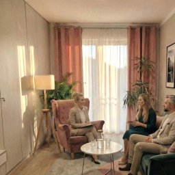 INTROS SPÓŁKA Z OGRANICZONĄ ODPOWIEDZIALNOŚCIĄ - Jasne wnętrze gabinetu z kobietą w fotelu prowadzącą rozmowę z parą siedzącą na kanapie. Na stoliku woda w dzbanku i szklanki. Delikatne, naturalne światło.