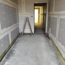 Sławomir Wojtuń - Wnętrze w trakcie prac wykończeniowych: ściany z płyt kartonowo-gipsowych, widoczne łączenia, drabina, instalacje podłogowe. Surowy stan przed dalszymi pracami.
