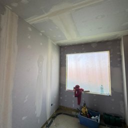 Sławomir Wojtuń - Pokój w trakcie prac wykończeniowych: ściany przygotowane do malowania, widoczne łączenia płyt, narzędzia i instalacja elektryczna przy podłodze.