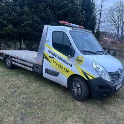 Jakub Piekarski - Biała laweta z żółtymi akcentami i napisem 'Pomoc Drogowa' na trawiastym terenie. Widoczne światła ostrzegawcze na dachu i numer telefonu.