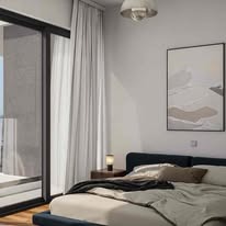 Jasna sypialnia z dużym oknem balkonowym, minimalistycznym łóżkiem i abstrakcyjnym obrazem na ścianie. Delikatne światło podkreśla nowoczesny design wnętrza.