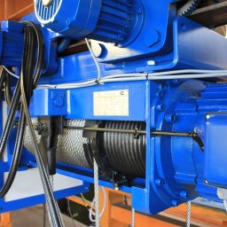 SDM DŹWIGI I WCIĄGNIKI Sp. z o.o. - Niebieski wciągnik linowy elektryczny z wózkiem jednoszynowym, widoczne silniki, liny i tabliczka znamionowa. Urządzenie przeznaczone do suwnic przemysłowych.