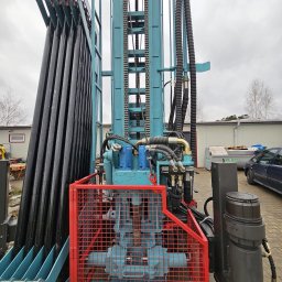 Wiertnica do studni głębinowych w Bełchatowie. Widoczne rury wiertnicze, hydraulika i zabezpieczenia. Sprzęt gotowy do pracy.