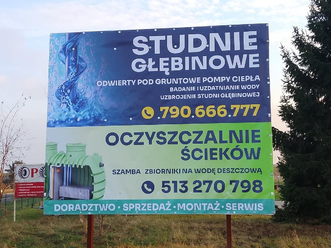Billboard reklamujący studnie głębinowe i oczyszczalnie ścieków z numerami telefonów. Widoczne grafiki studni i przekrój oczyszczalni. Doradztwo, sprzedaż, montaż, serwis.