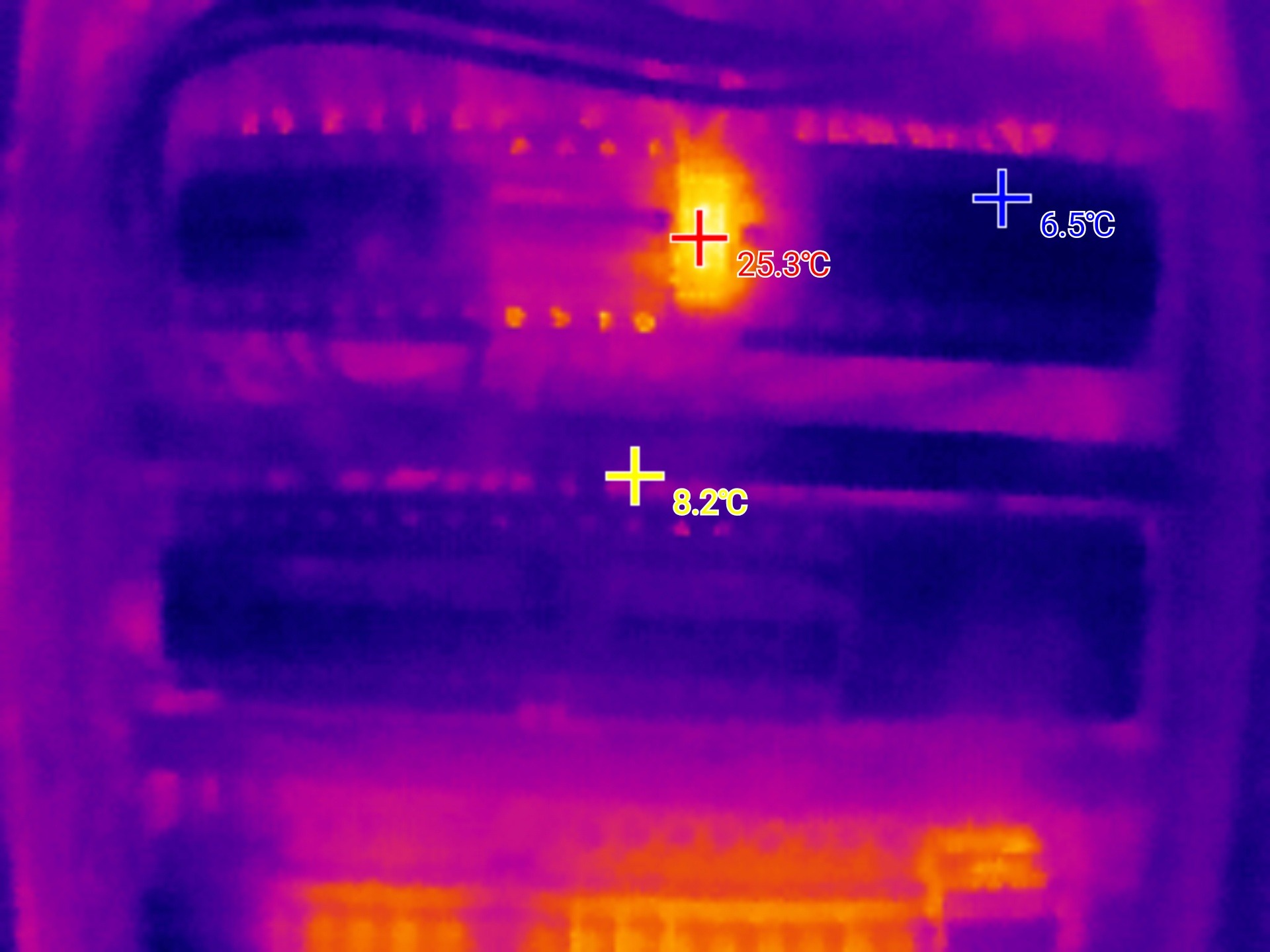 Termowizja rozdzielnicy elektrycznej ukazuje temperaturę poszczególnych elementów, z zaznaczonym punktem o podwyższonej temperaturze 25.3°C.