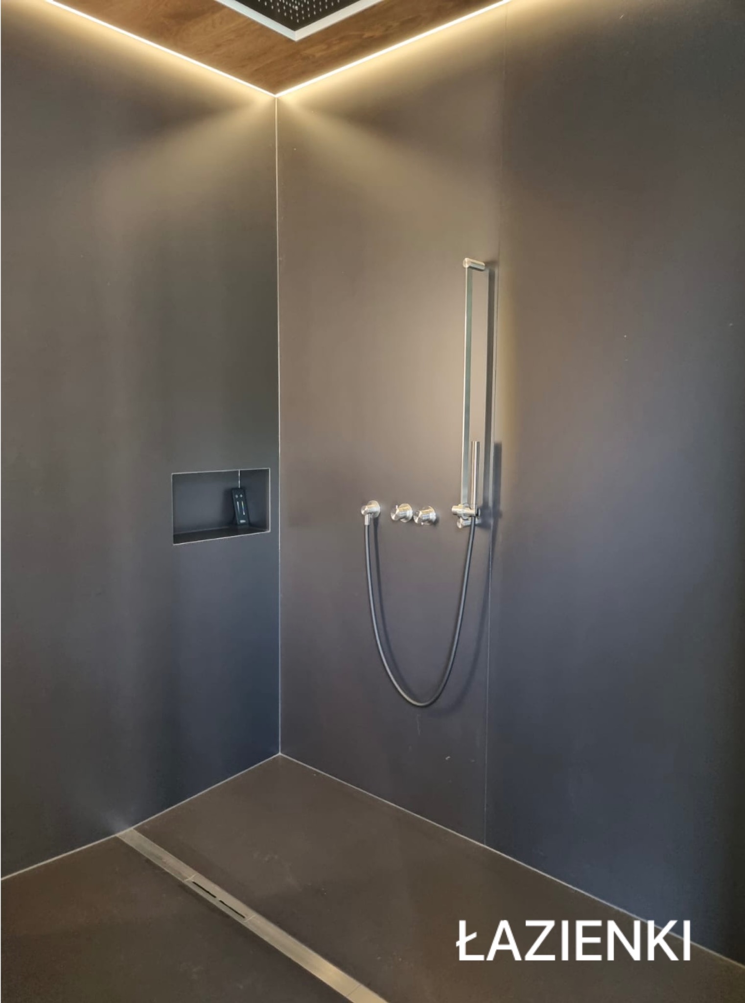 Nowoczesna kabina prysznicowa w ciemnej tonacji z oświetleniem LED, chromowaną armaturą i wnęką na kosmetyki. Minimalistyczny design z odpływem liniowym.