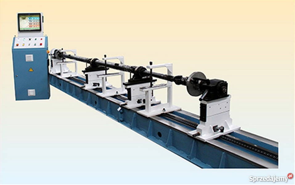 Wyważarka do wałów napędowych z długim wałem zamocowanym w uchwytach, z panelem sterowania po lewej stronie. Precyzyjne wyważanie wałów kardana.