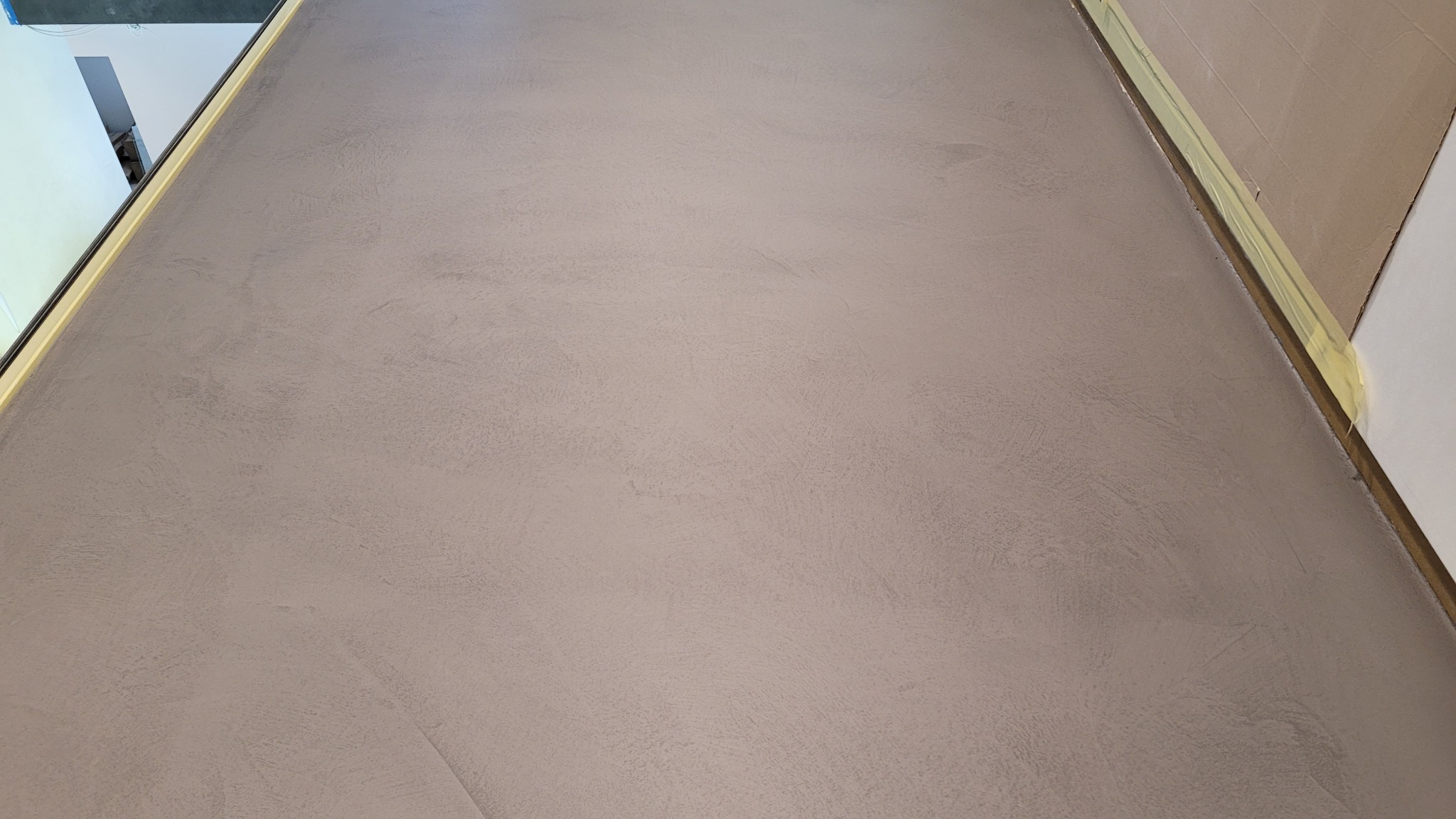 Szara, gładka powierzchnia z delikatną teksturą, zabezpieczona taśmą malarską przy krawędziach. Widoczne subtelne niuanse kolorystyczne i charakterystyczny wzór.