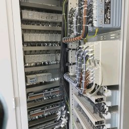 EL-KAR Karol Napora - Rozdzielnica elektryczna z licznymi przewodami i elementami sterującymi, widok z bliska na uporządkowane okablowanie wewnątrz szafy sterowniczej.