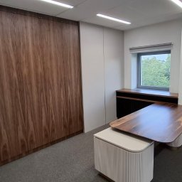 Formedge - Nowoczesne biuro z drewnianą zabudową szaf wnękowych, biurkiem z blatem drewnianym i tapetą w kwiaty. Minimalistyczny design, jasne oświetlenie.