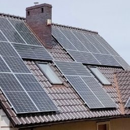 PSK Sp. z o.o. - Panele słoneczne na dachu domu z brązową dachówką, widoczne okna dachowe i komin. Instalacja fotowoltaiczna na skośnym dachu.