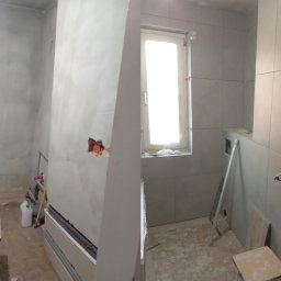 Tomasz Pasternak - Zdjęcie 'przed i po' prezentujące remont łazienki: po lewej surowe ściany, po prawej wyłożone jasnymi płytkami, z widoczną drabinką i instalacją elektryczną.