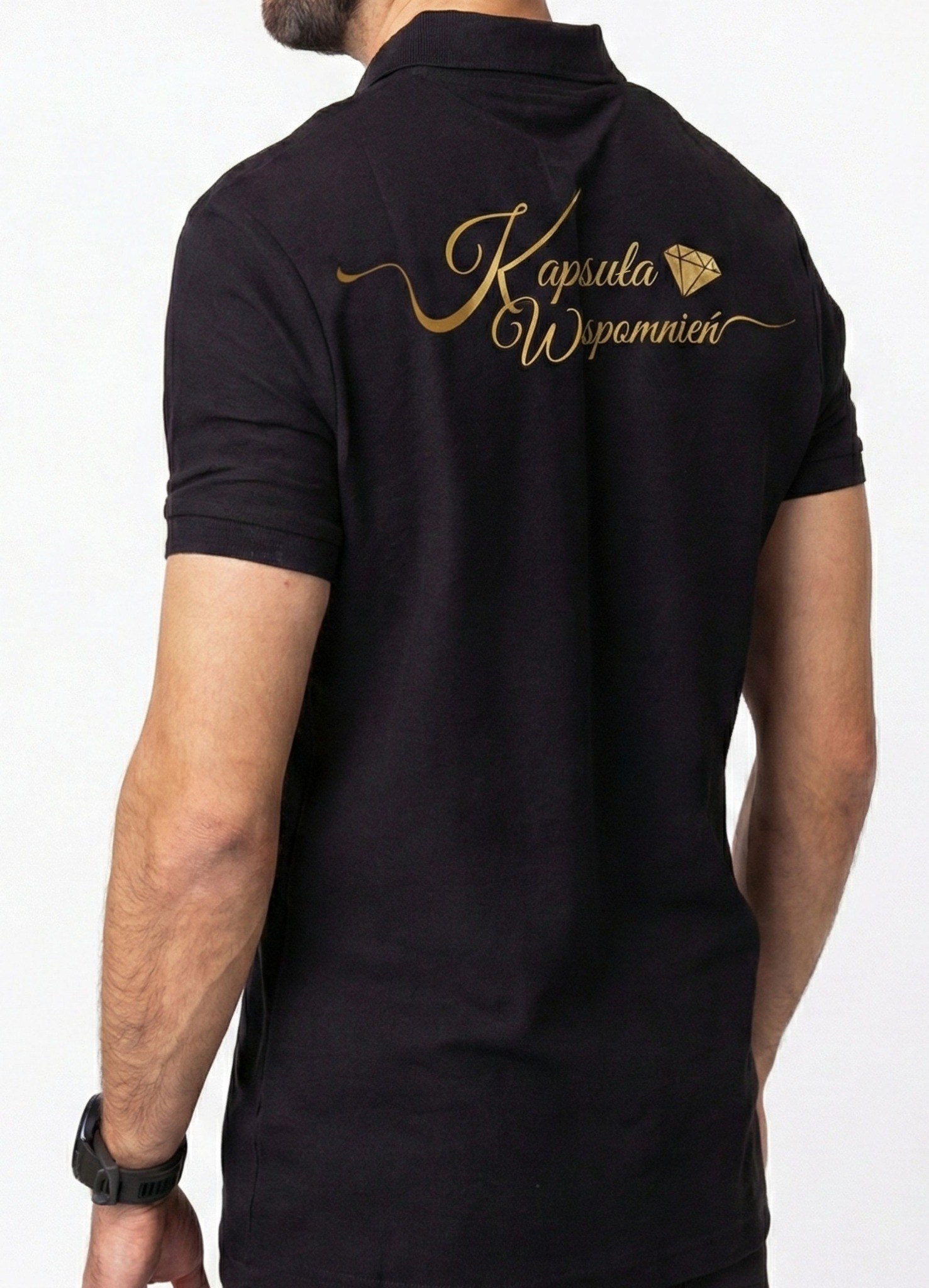 Czarna koszulka polo z nadrukiem w kolorze złotym 'Kapsuła Wspomnień' z motywem diamentu, widok z tyłu na białym tle. Precyzyjny nadruk na odzieży.
