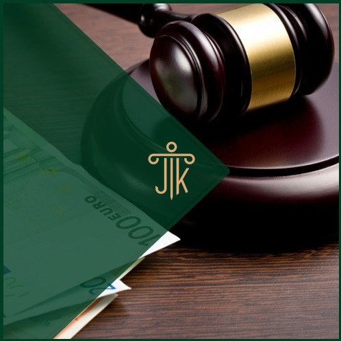 Młotek sędziowski na drewnianym stole z banknotami euro, częściowo zasłonięty zielonym filtrem z logo kancelarii. Symbol spraw gospodarczych i finansowych.