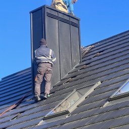 NFO-DACH Filip Wróblewski - Praca dekarzy na dachu z oknami połaciowymi i kominem w Stargardzie. Dwóch mężczyzn w odzieży roboczej wykonuje prace na wysokości, na tle błękitnego nieba.