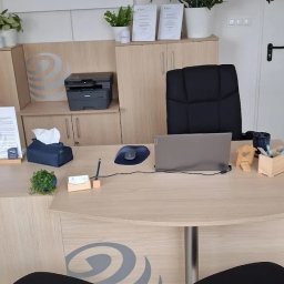 SMG Auto Serwis Krzysztof Śmigielski - Biuro ubezpieczeniowe z biurkiem, laptopem, krzesłami dla klientów i logo firmy 'Dom Ubezpieczeniowy Spectrum' na ścianie. Wnętrze jasne, z roślinami doniczkowymi.