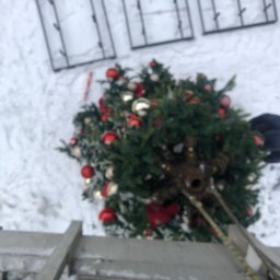 SkyCloud Ruslan Okilka - Montaż dekoracji świątecznych na wysokości: choinka z bombkami i drabina na tle zaśnieżonego dachu i okien. Widok z góry, perspektywa pracownika.