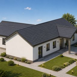 USŁUGI PROJEKTOWE Damian Brzyski - Nowoczesny dom parterowy z ciemnym dachem i białymi elewacjami, otoczony zadbanym ogrodem z oświetlonymi ścieżkami i zielonym trawnikiem. Ujęcie z góry.