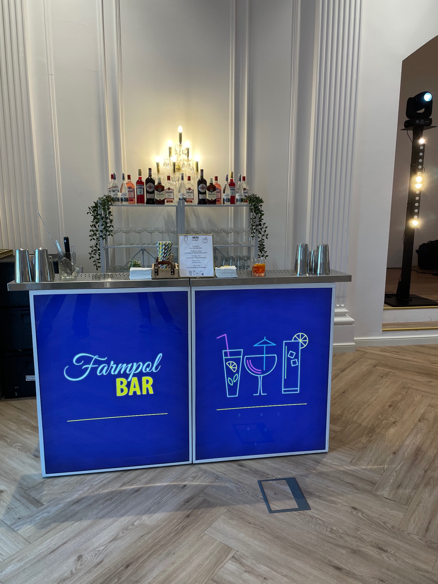 Mobilny bar Farmpol z podświetlanym panelem, koktajlami i dekoracjami na przyjęciu. Profesjonalny sprzęt barmański i oświetlenie eventowe w tle.