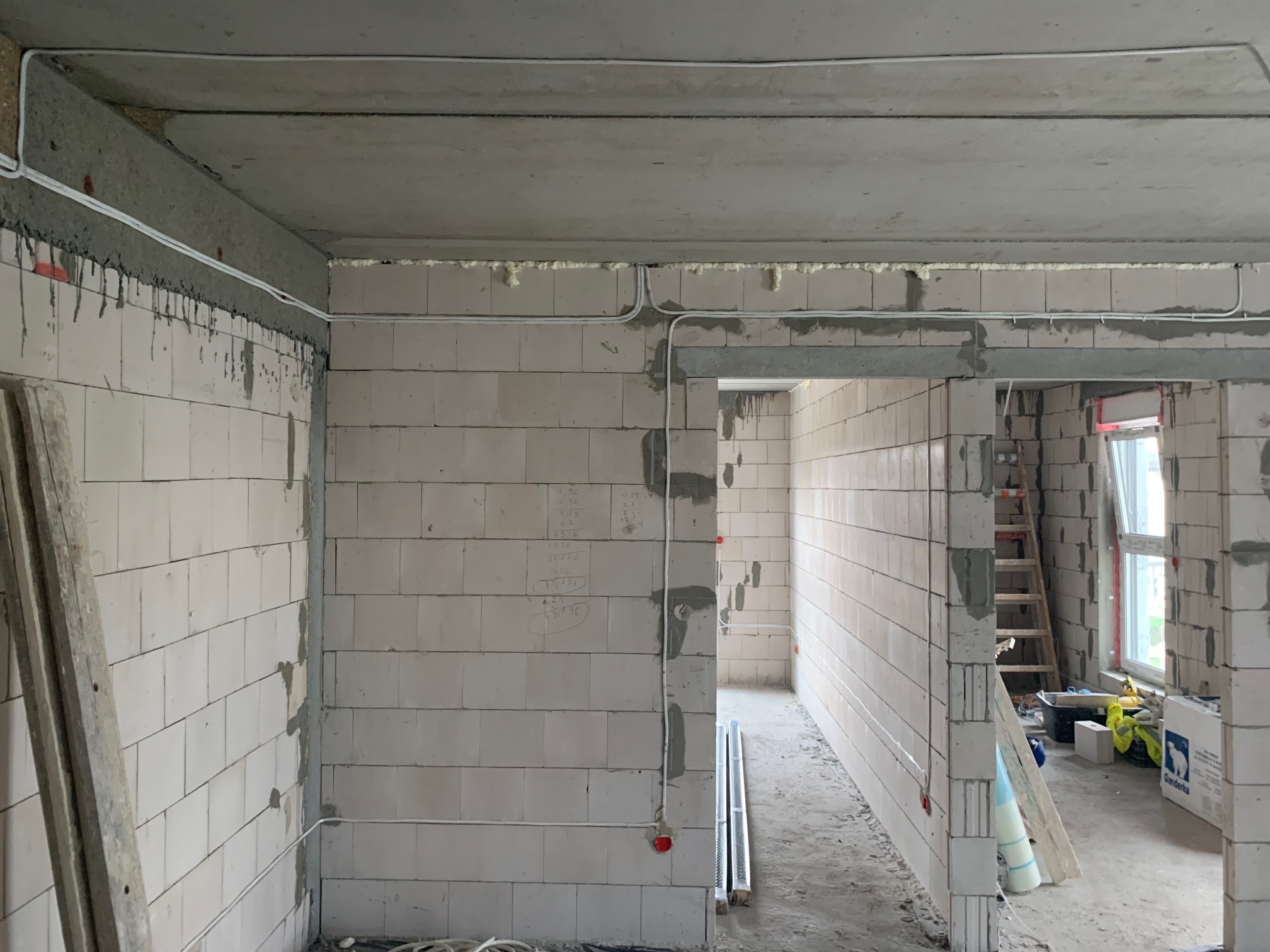 Bydgoszcz: Wnętrze w trakcie prac, widoczne białe przewody elektryczne prowadzone po ścianach z betonu komórkowego, surowy stan wykończenia.