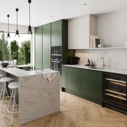 Michał Góral U3D - Nowoczesna kuchnia z wyspą i zielonymi szafkami, parkiet w jodełkę, widok na taras przez rozsuwane drzwi. Minimalistyczne lampy wiszące nad wyspą.