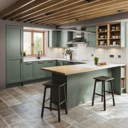 Michał Góral U3D - Nowoczesna kuchnia w odcieniach zieleni z drewnianymi akcentami, wyspą i dwoma stołkami barowymi. Widok na ogród przez przesuwne drzwi.