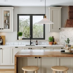 Michał Góral U3D - Jasna kuchnia w stylu klasycznym z marmurowym blatem, drewnianym barkiem i czarnymi akcentami. Widok na okno z zielenią. Na blacie dekoracje i owoce pod kloszem.