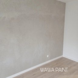 VLADLEN HRYBACHOV - Wykończone wnętrze: ściana z dekoracyjną, beżową fakturą, biała listwa przypodłogowa i jasna podłoga. Widoczny fragment gniazdka elektrycznego.